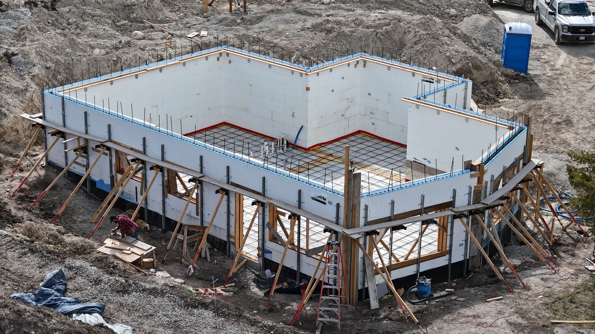 An aerial view of a building under construction in the middle of a dirt field.