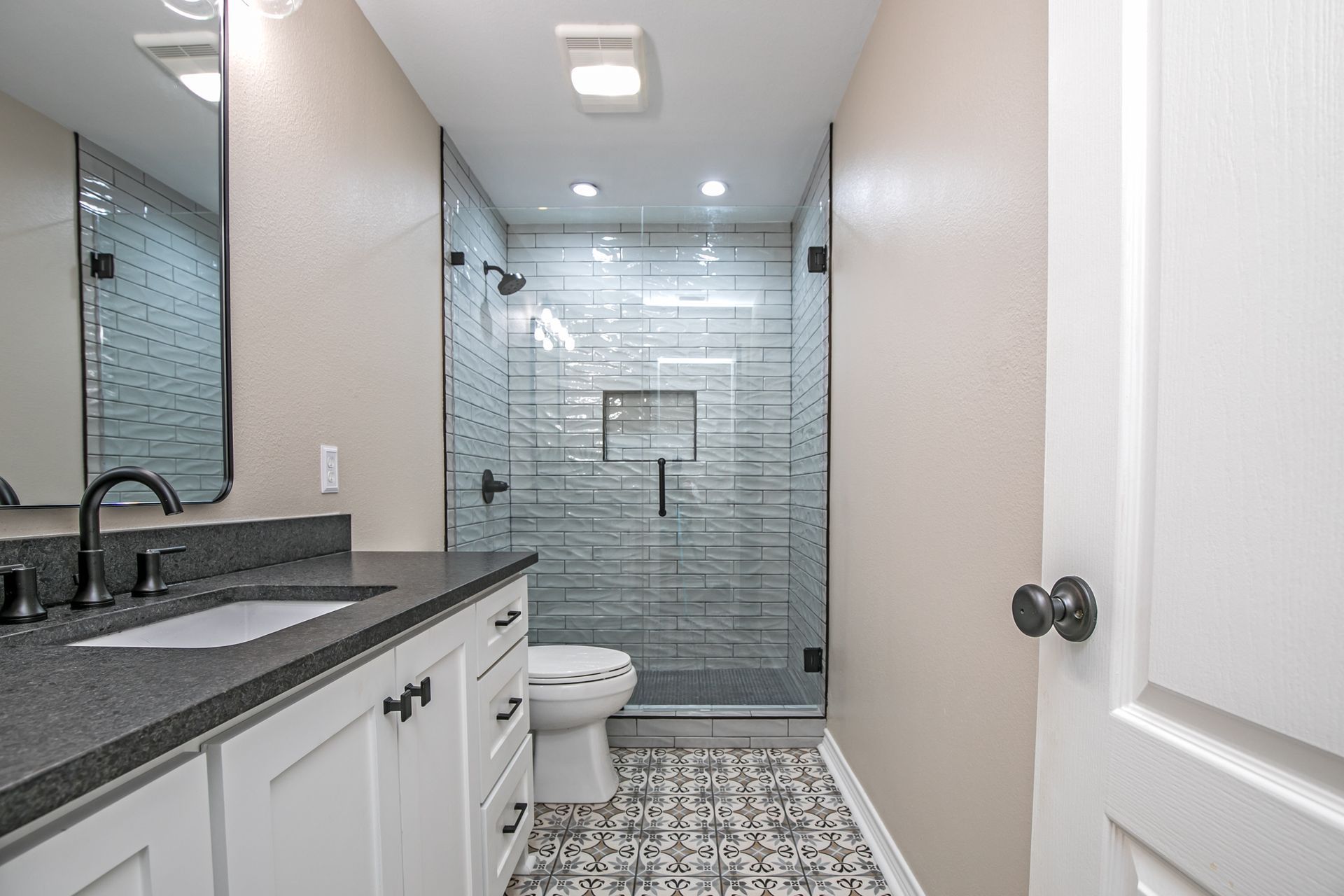A bathroom with a toilet , sink , mirror and walk in shower.