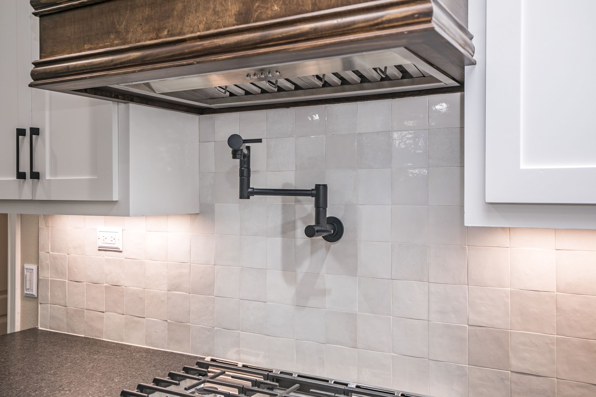 A kitchen with a stove top oven and a faucet on the wall.