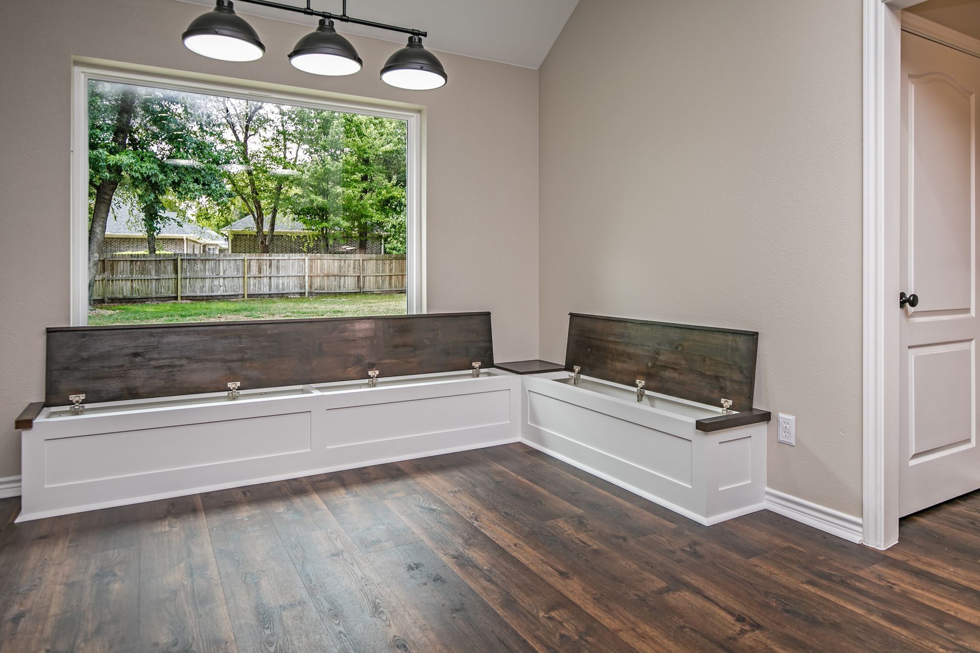 There is a bench in the corner of the room with a large window.