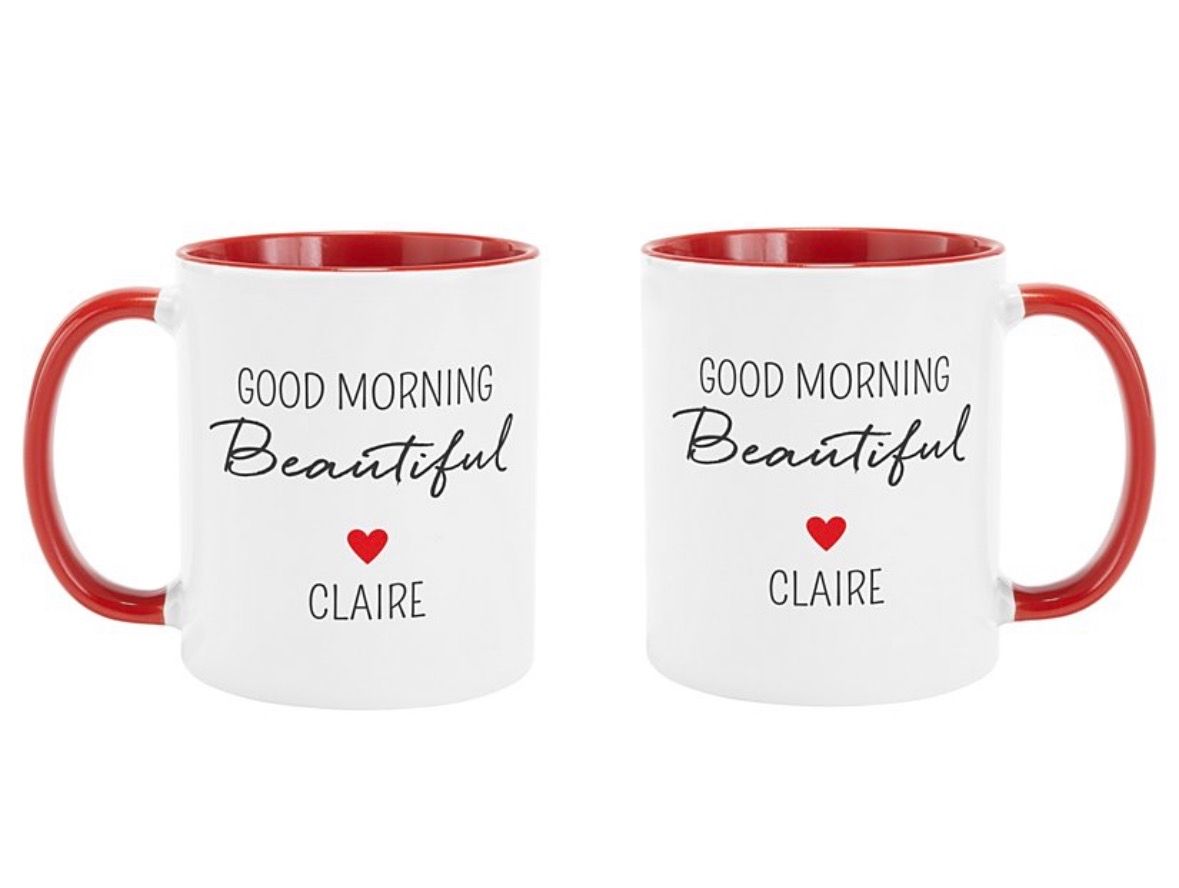 Two white mugs with red handles and interior. Text on the mugs reads 