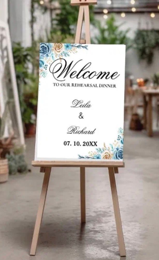 Wedding welcome sign on a wooden easel, with blue and gold floral accents.