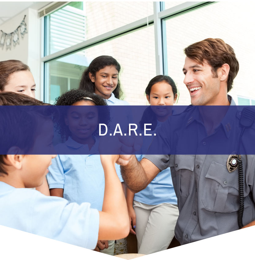A man in a police uniform is talking to a group of children with the words d.a.r.e.