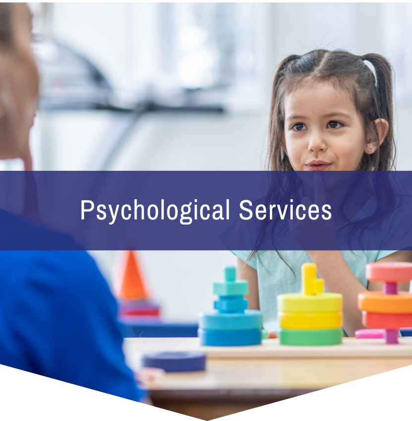 A little girl is sitting at a table with a stack of colorful blocks and a sign that says psychological services