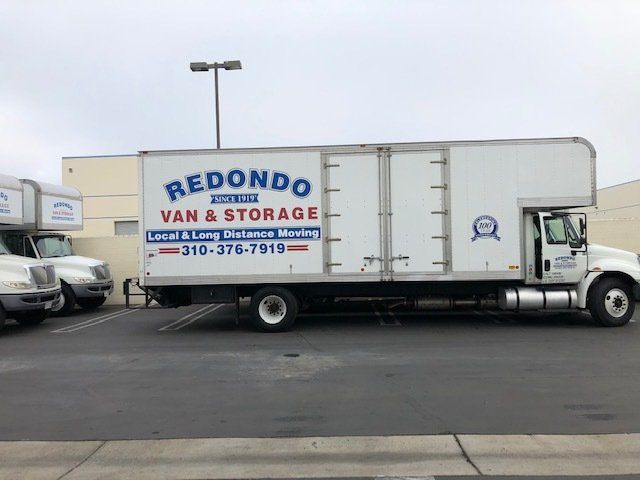 A moving company truck is parked in a lot with a large storage container.