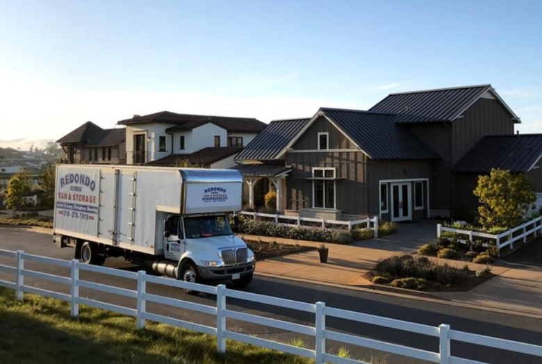 Moving truck parked on a suburban street in front of modern houses at sunset