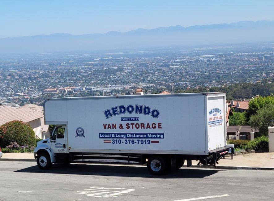 Moving truck with Redondo Van & Storage truck parked on a hillside overlooking a cityscape.