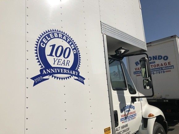 Moving truck with a 100-year anniversary logo on the side panel.
