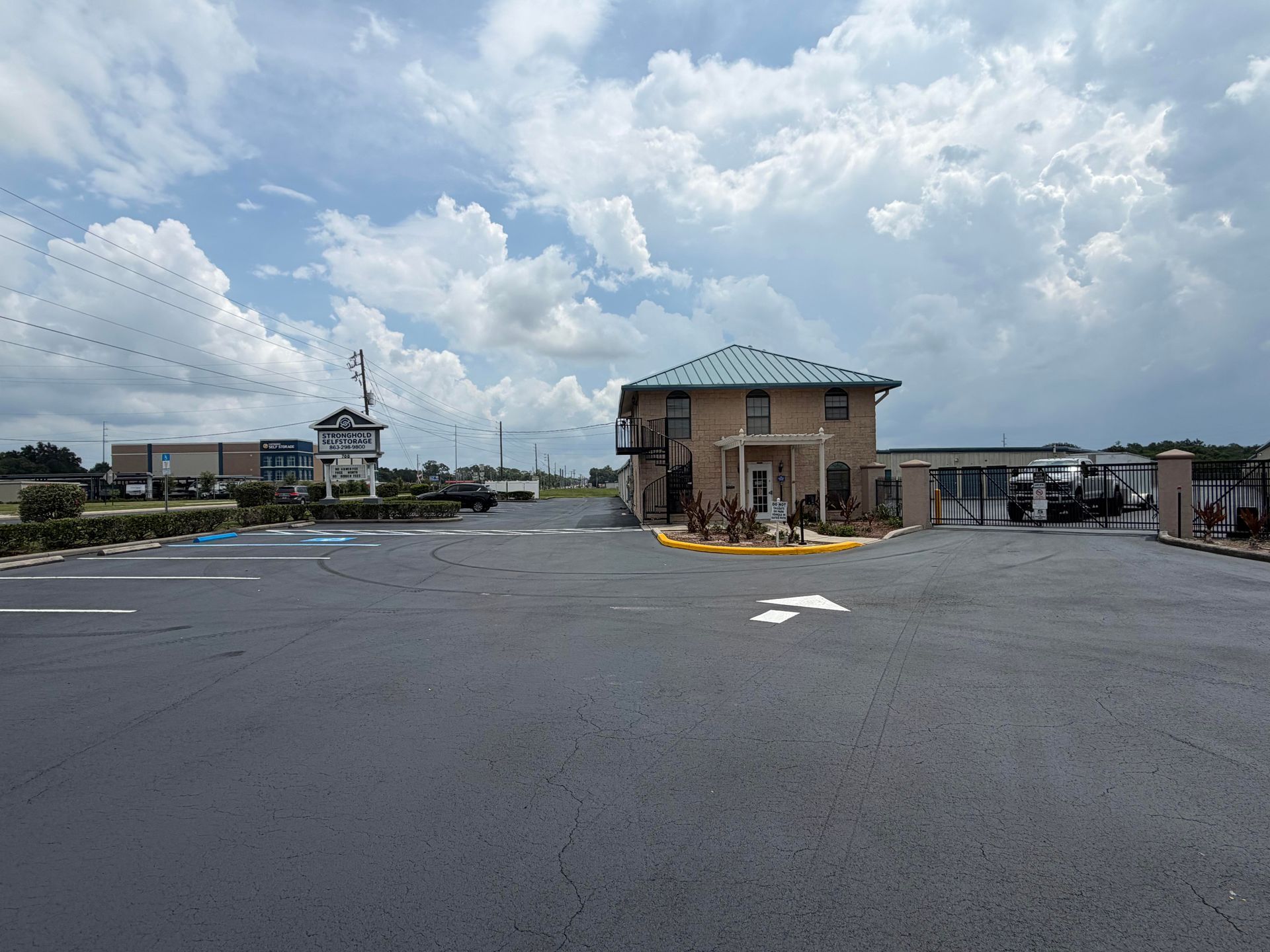 Empty parking lot with a small building under a cloudy sky