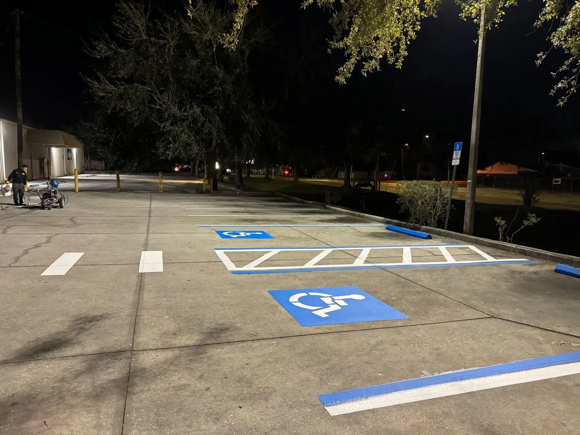 Nighttime parking lot with blue handicapped spaces and white striped access aisles.