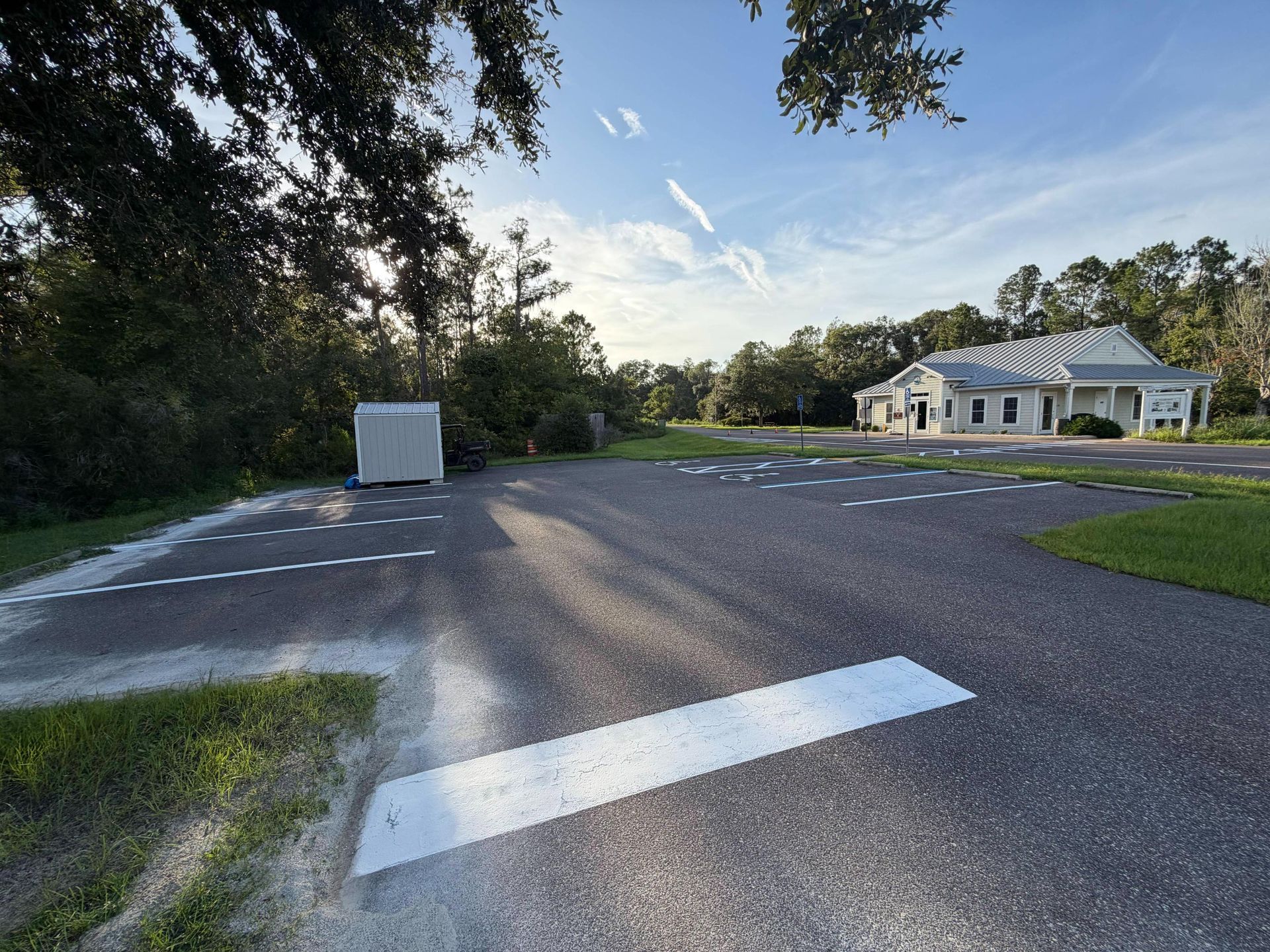 Empty parking lot with white painted lines beside a small white building at sunset
