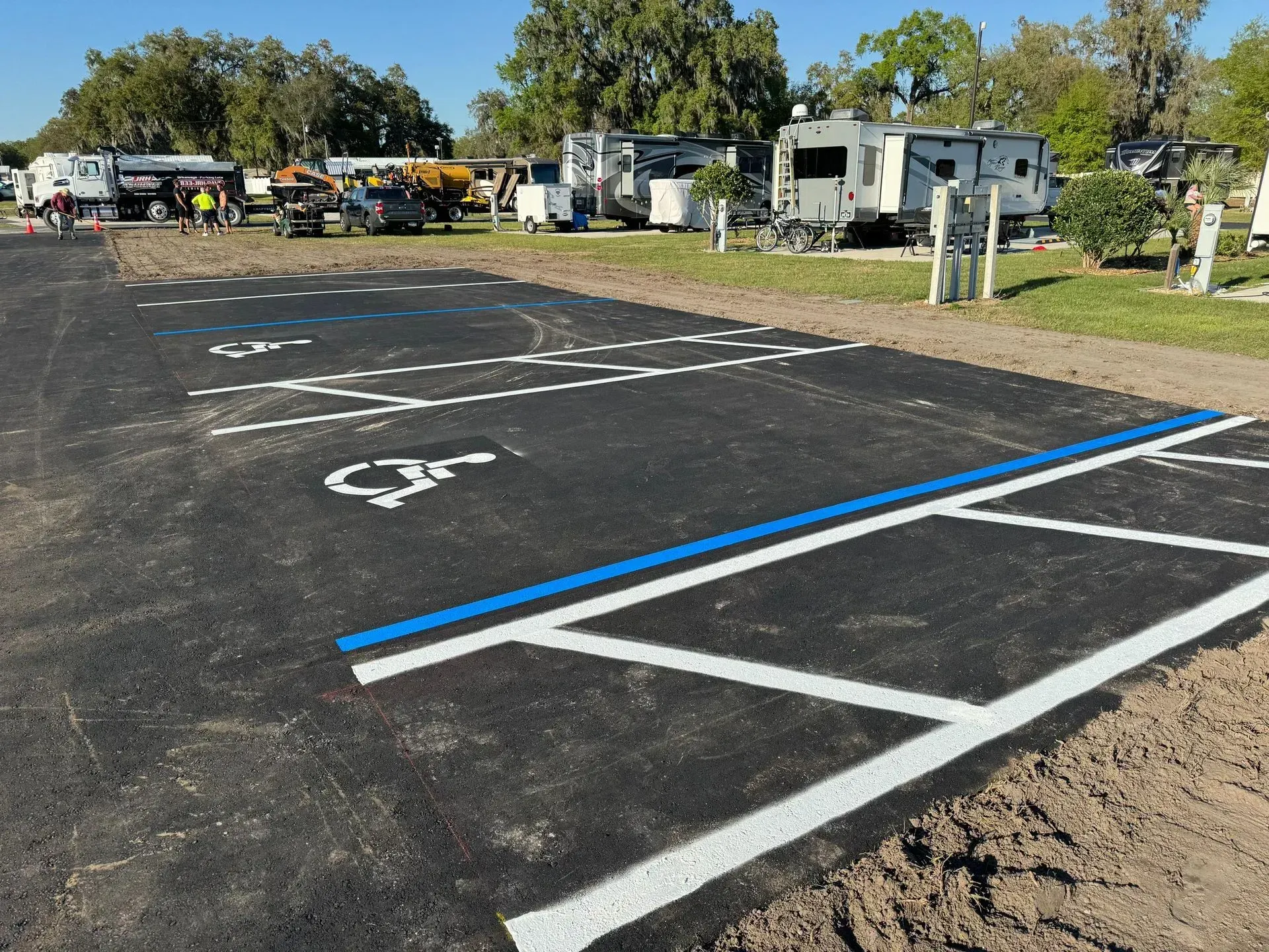 Accessible parking spaces in a paved lot, marked with white and blue lines near RVs.