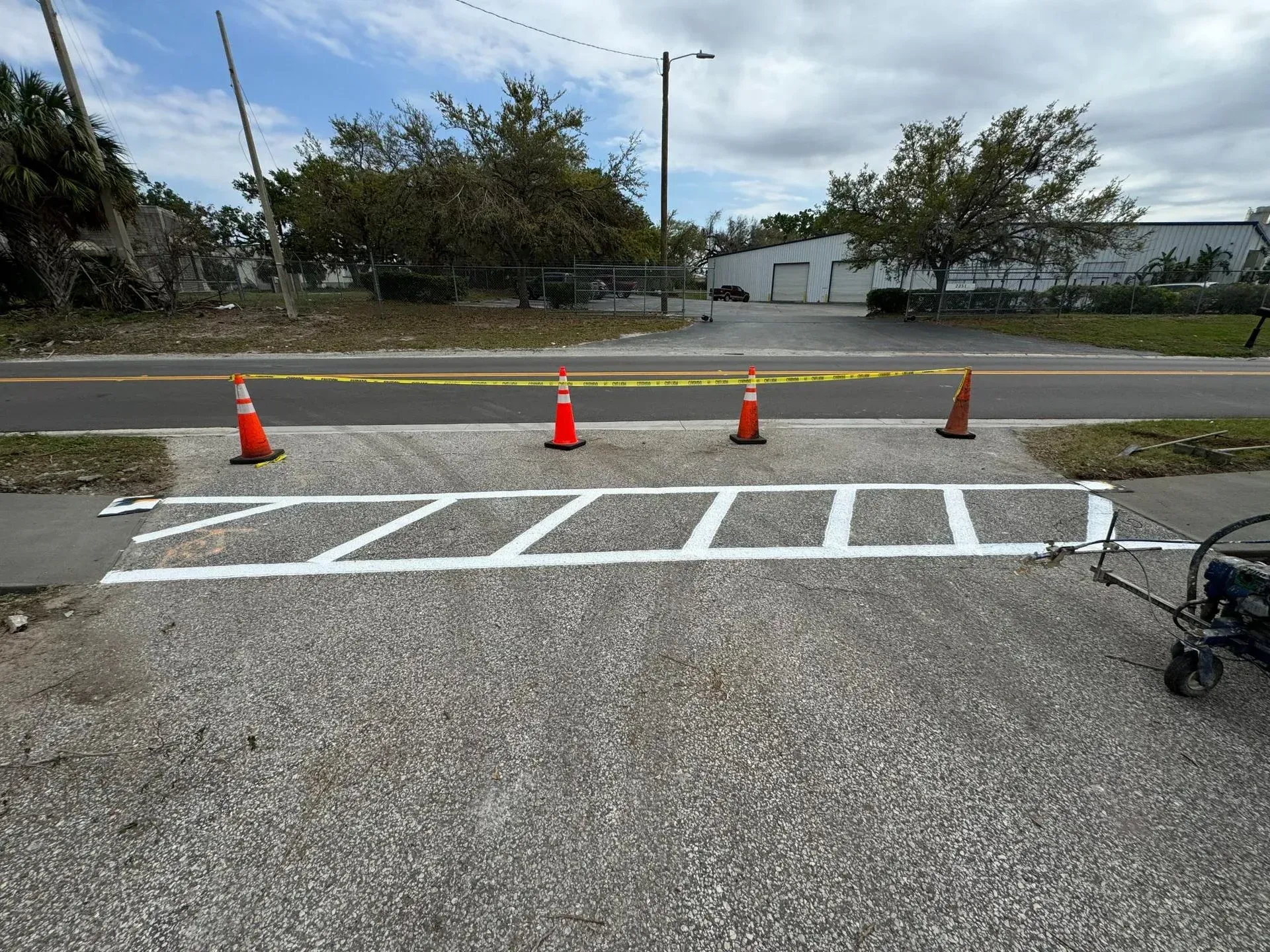 Roadside parking area with white diagonal markings and orange cones blocking the curb.