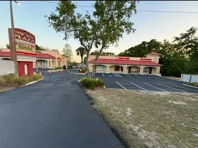 Empty parking lot beside a red-roofed building at dusk