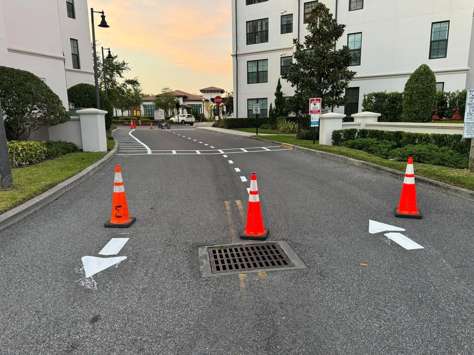 Orange traffic cones blocking a road drain on a residential street at dusk