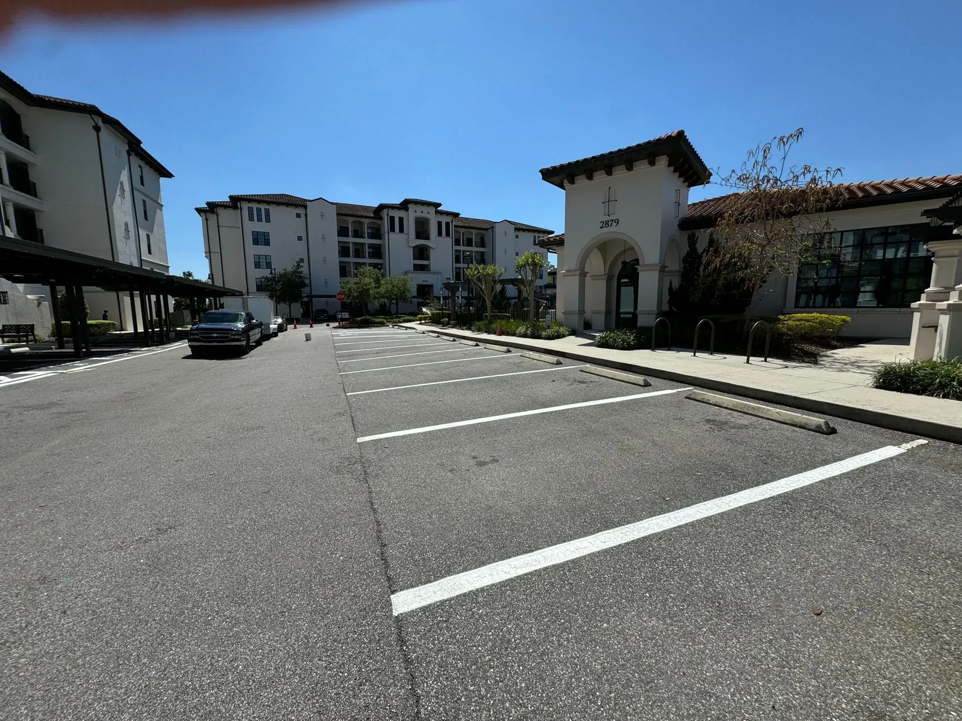 Empty parking lot beside apartment buildings under a clear blue sky