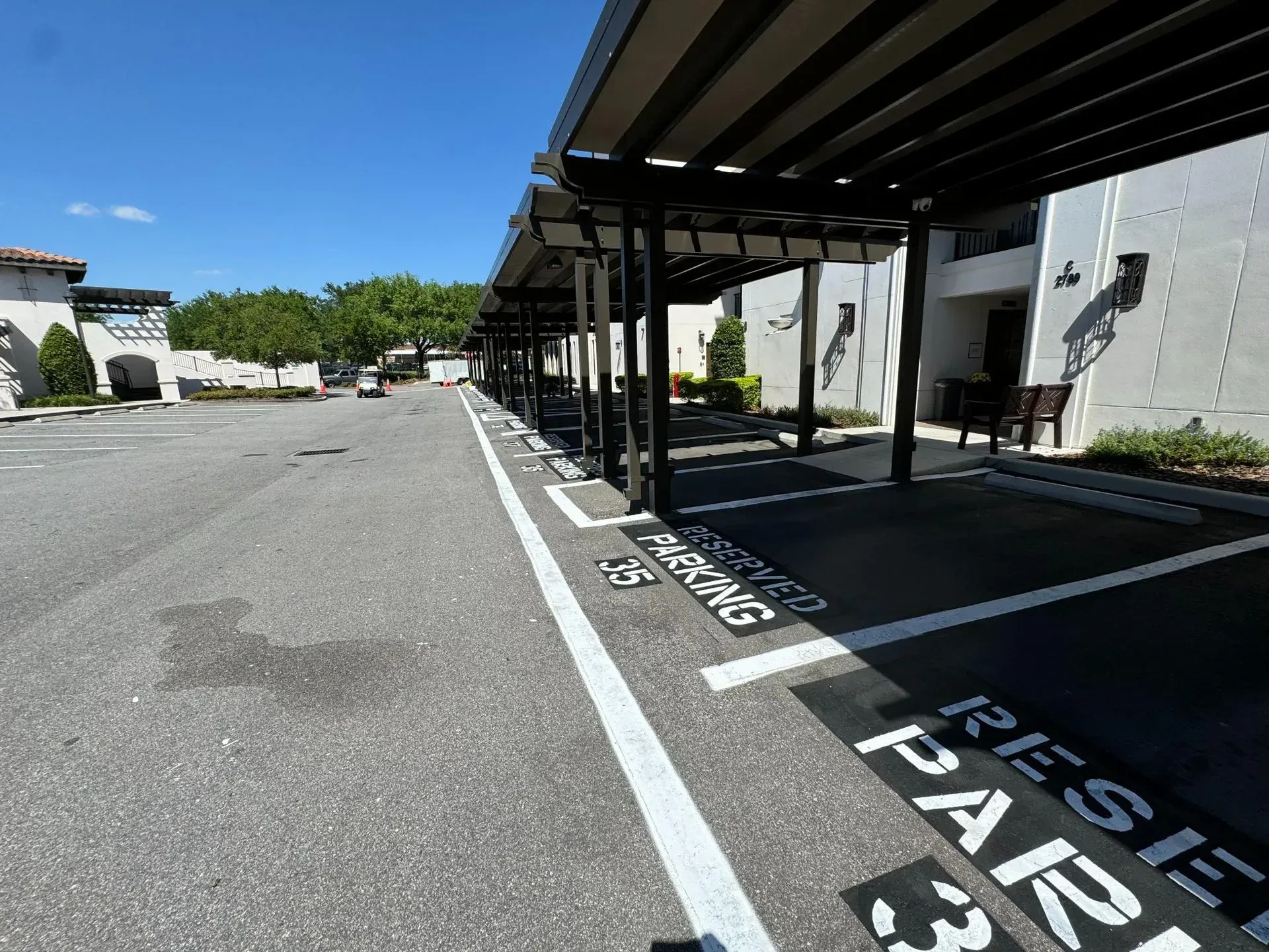 Covered parking spaces marked “RESERVED PARKING” beside a building on a sunny day