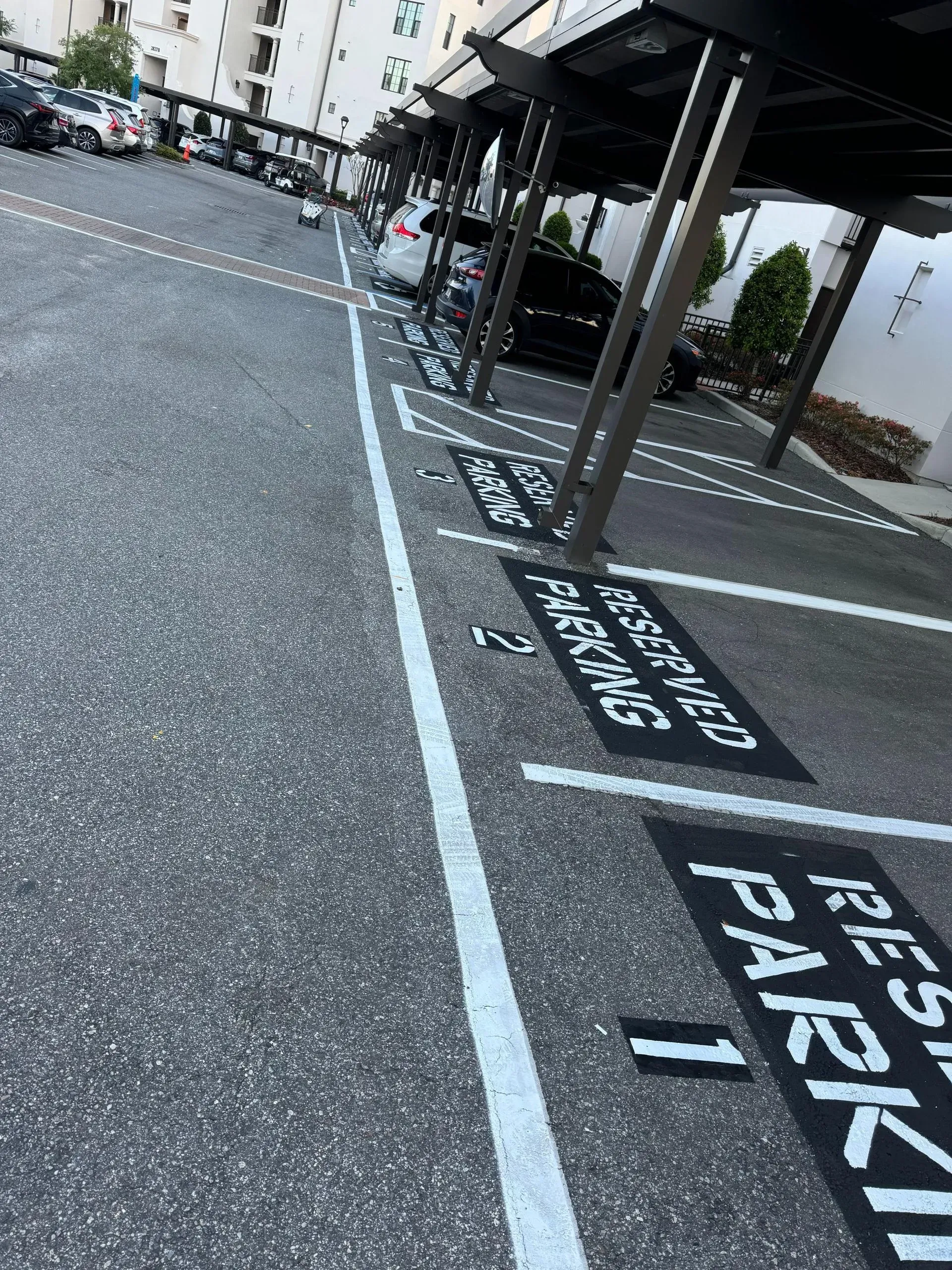 Parking spaces with black-and-white EV charging and reserved parking markings under a covered structure.