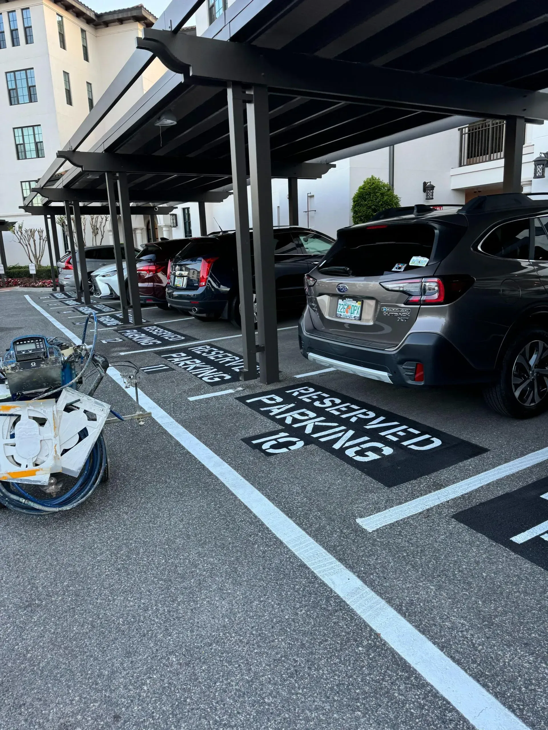 Covered parking spaces with cars, one marked “HANDICAP ONLY,” and scattered broken glass on the ground.