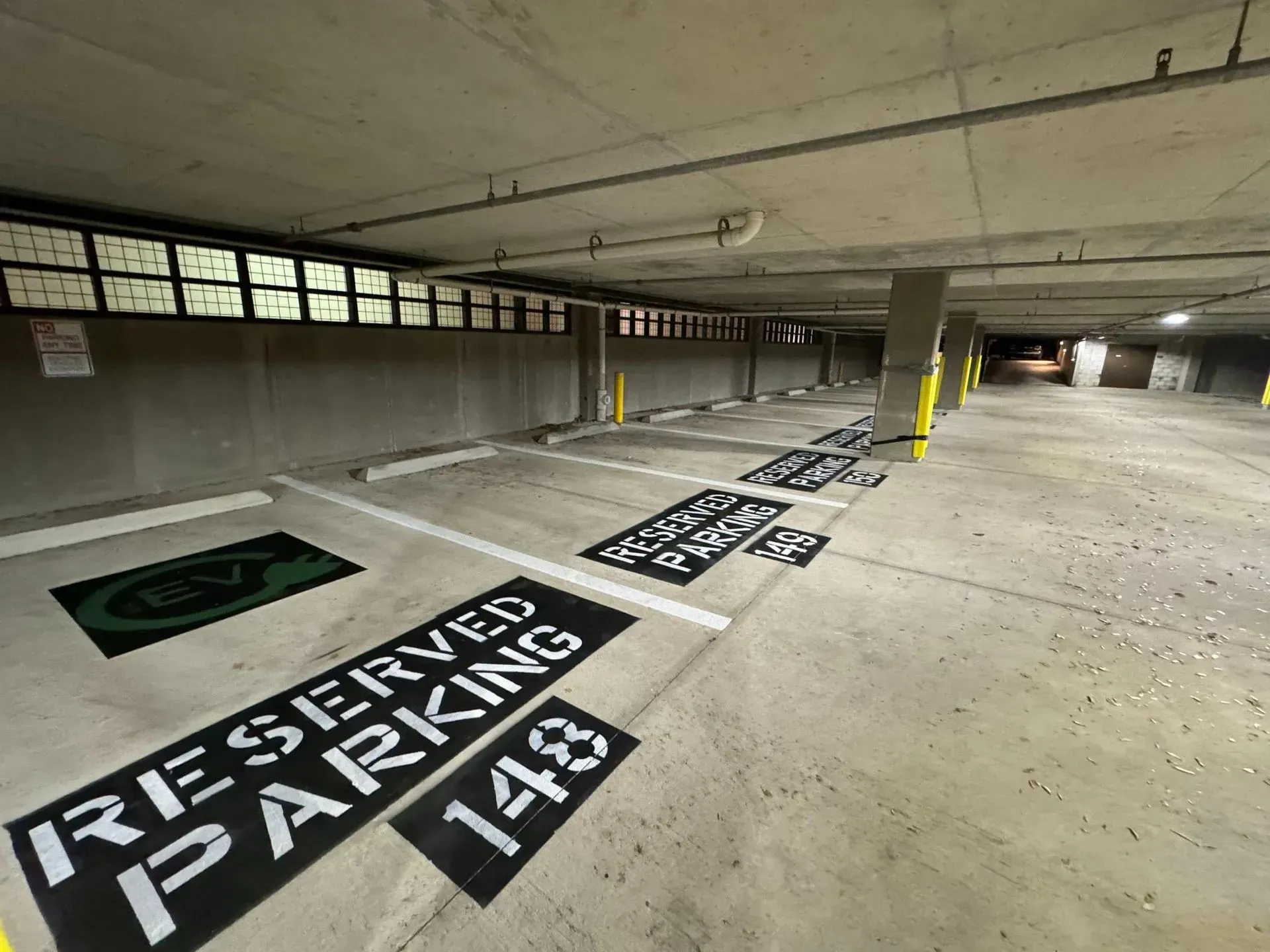 Reserved parking spaces in a concrete underground garage, marked with white stencil text.