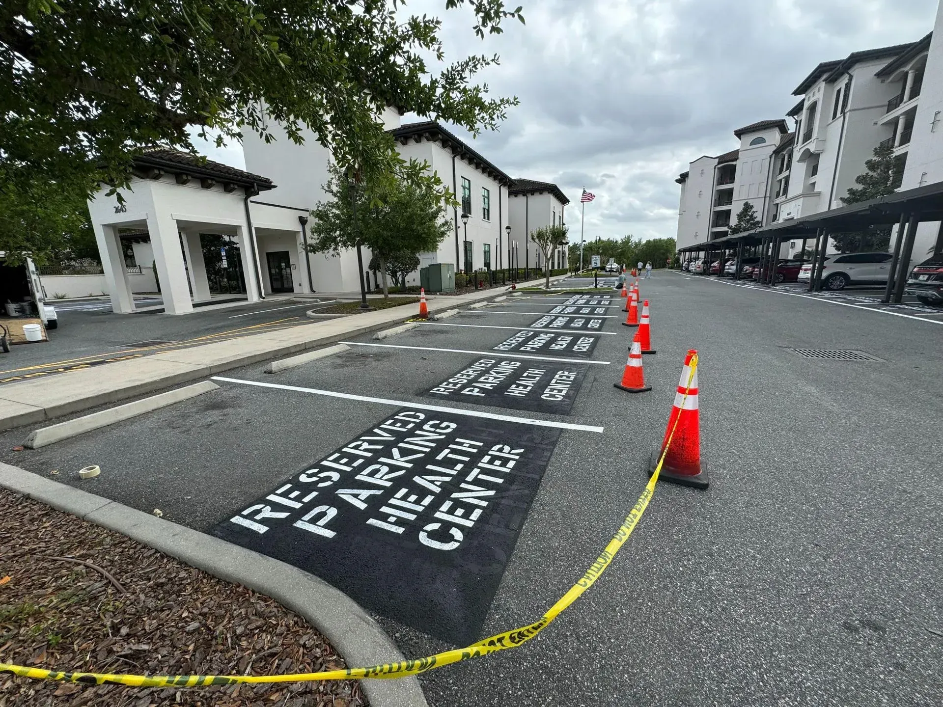 Marked parking spaces with white stencils and orange cones on a residential street under construction.
