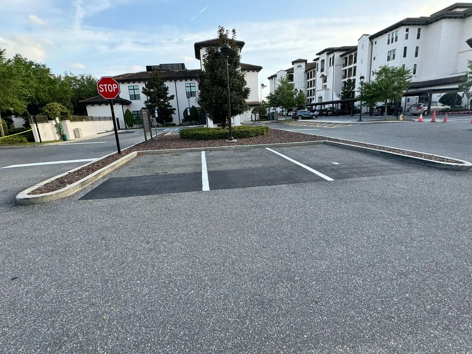 Empty parking lot with painted spaces, a stop sign, and apartment buildings in the background