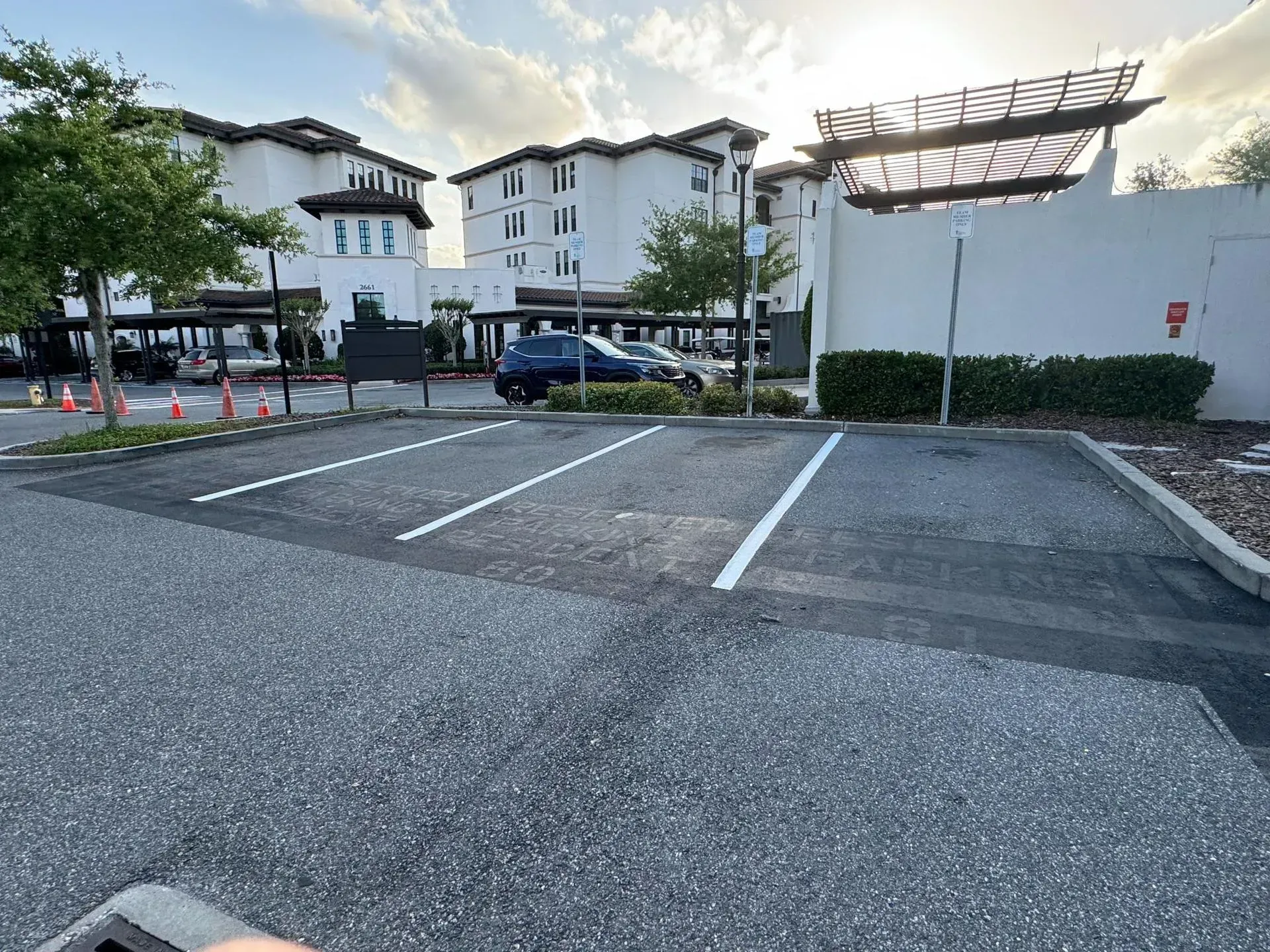Empty parking spaces beside a white apartment building at sunset