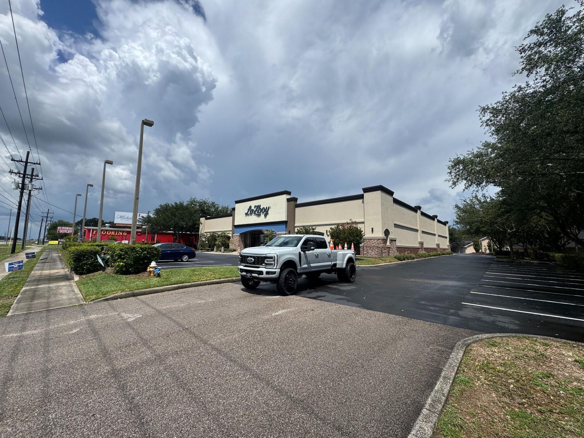 White pickup in parking lot beside a beige Jiffy store under cloudy sky