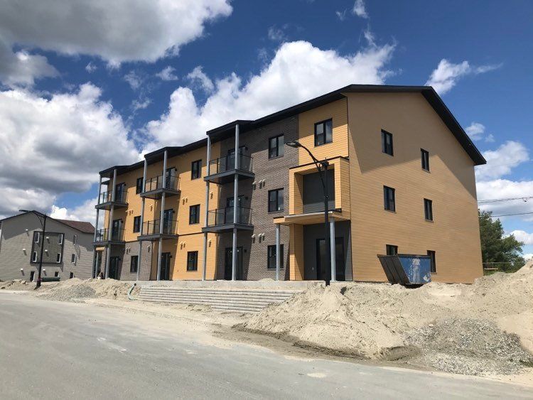 Un bâtiment en construction avec une benne à ordures devant