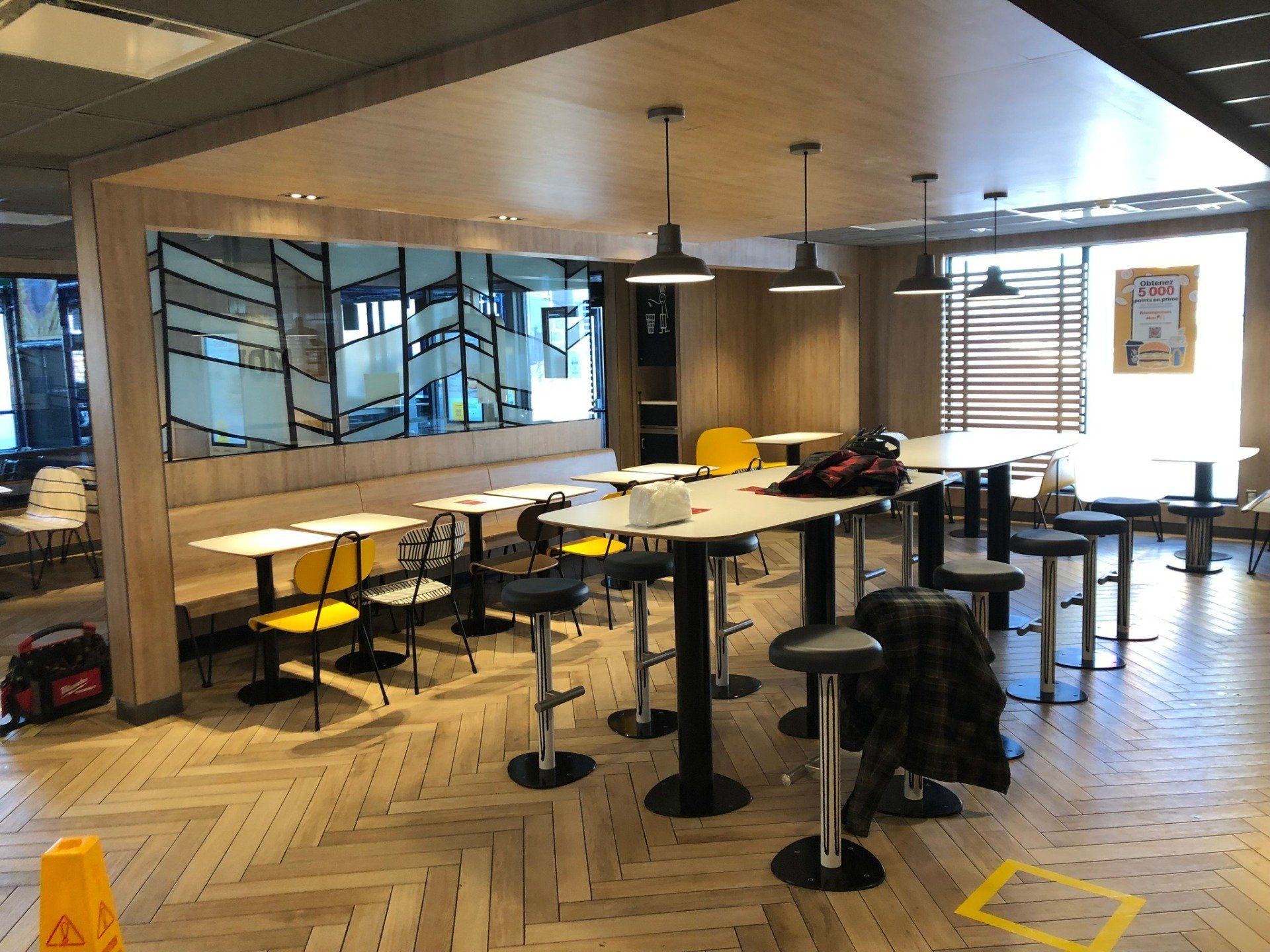 Un restaurant avec des tables et des chaises et un panneau jaune indiquant le sol mouillé.
