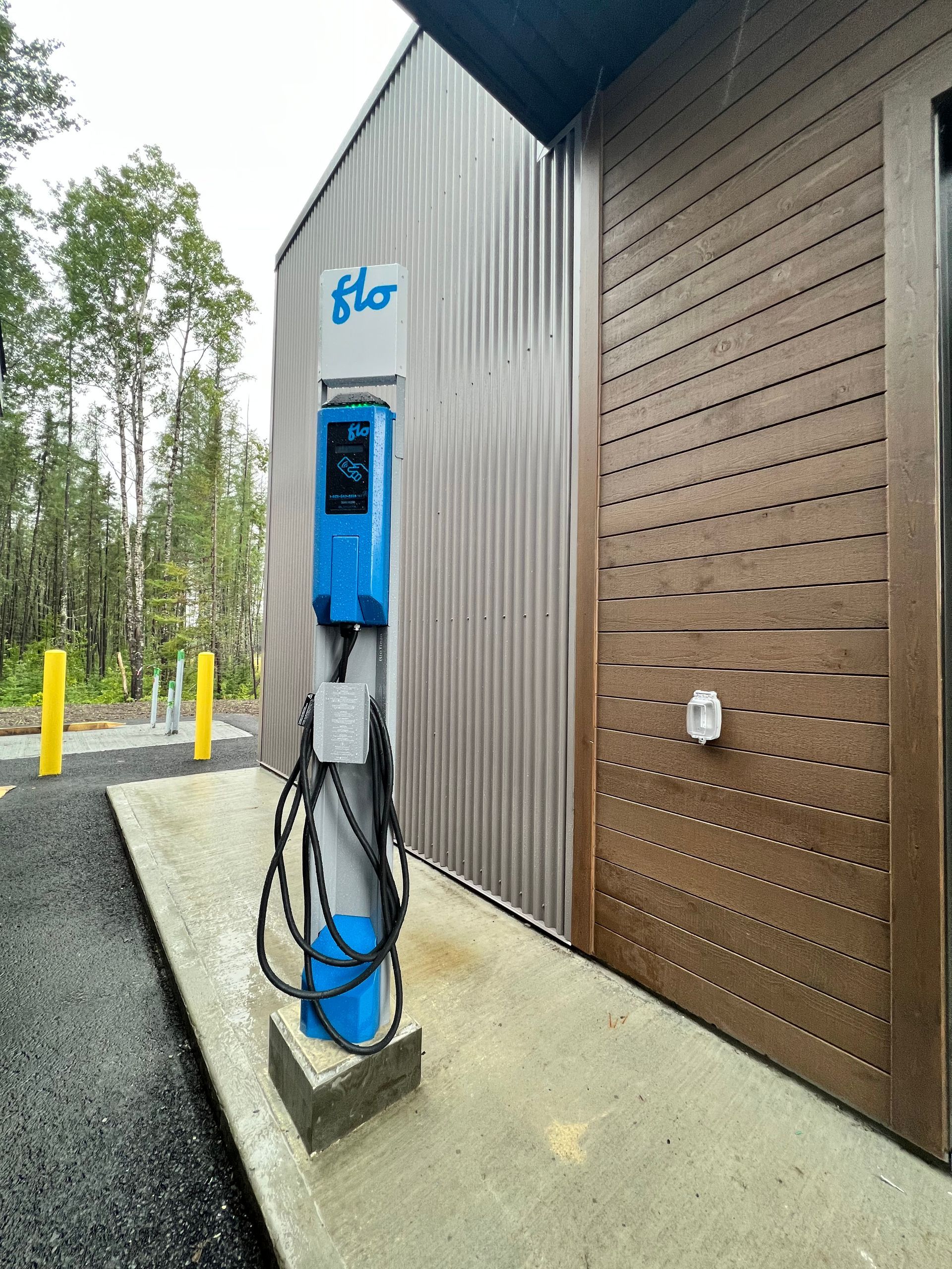 Une borne de recharge bleue pour véhicules électriques se trouve à l'extérieur d'un bâtiment.