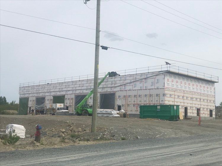 Un grand bâtiment est en construction à côté d'une route.