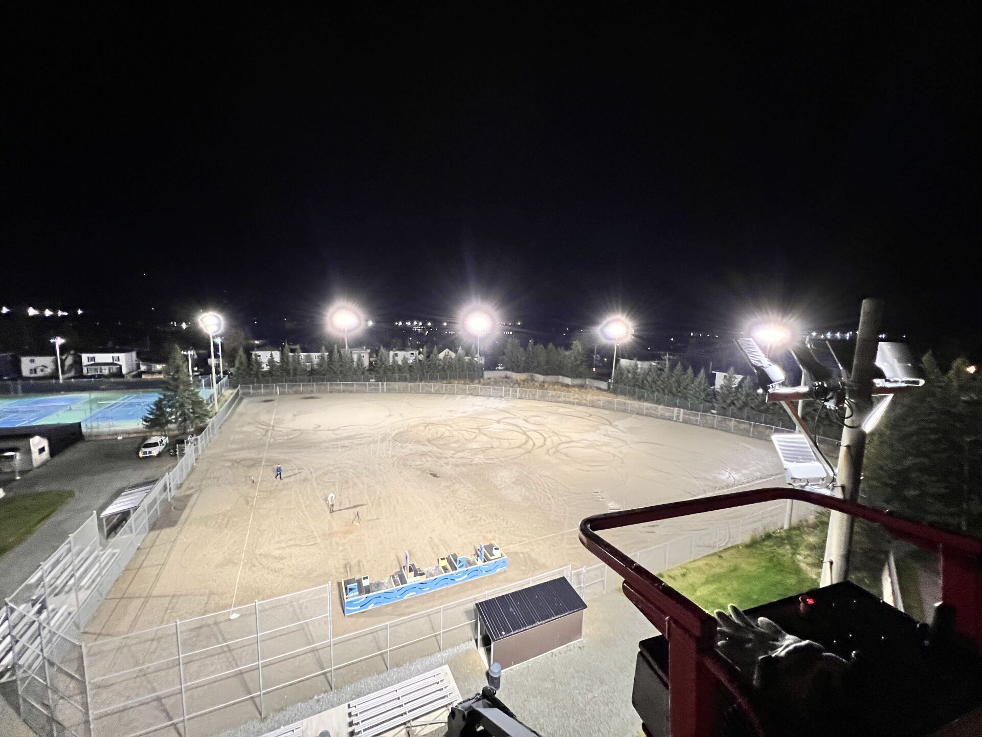 Un terrain de basket est éclairé la nuit avec beaucoup de lumières.