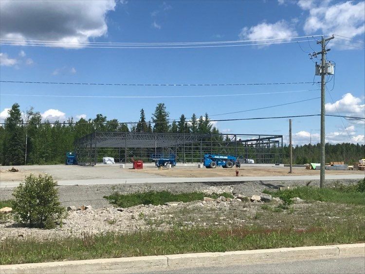 Une grande structure métallique est en cours de construction sur le bord de la route.