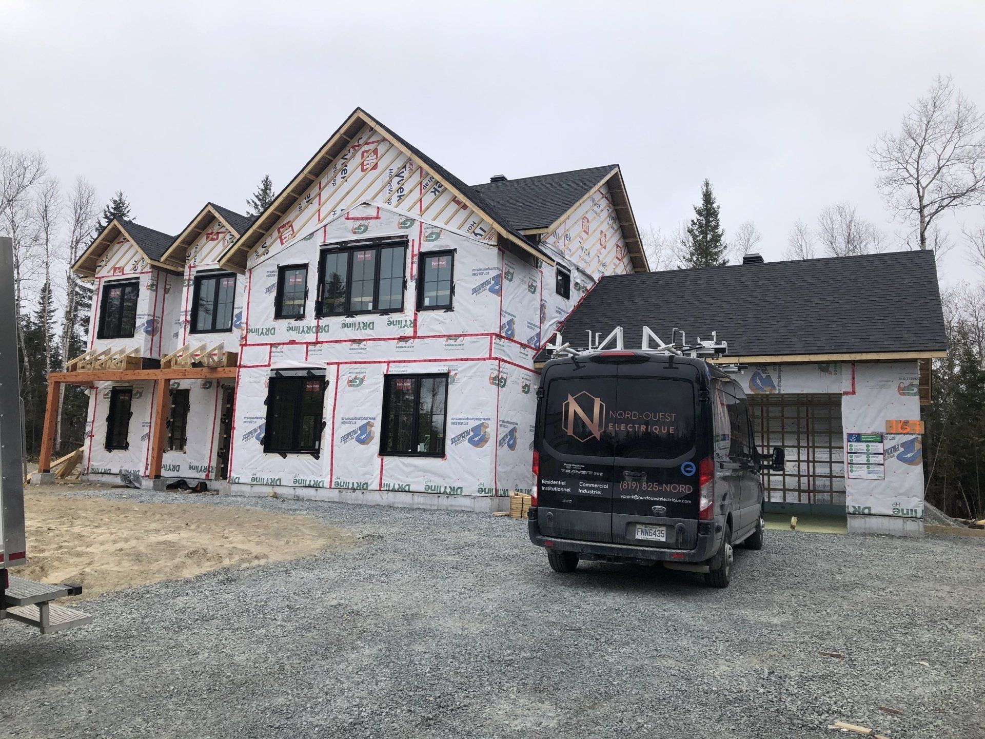 Une grande maison en construction avec une camionnette garée devant.