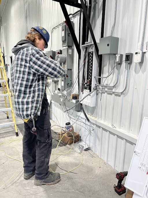 Un homme travaille sur des fils électriques dans un bâtiment.