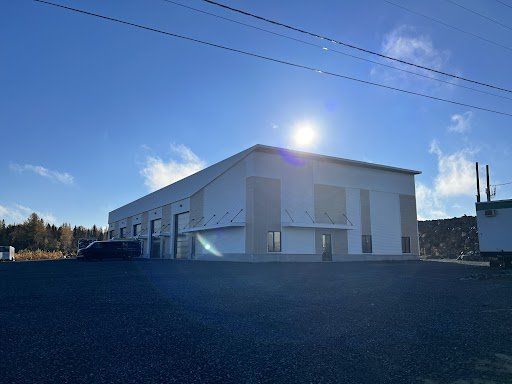 Un grand bâtiment blanc se trouve au milieu d'un parking.