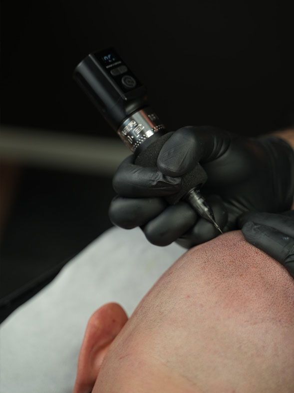 Hand med handske som använder en tatueringsmaskin på huden under en tatueringssession
