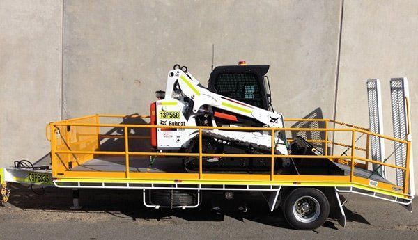 A Bobcat Tractor Is Sitting on Top of A Beautiful Flatbed Truck — Welshpool, WA — PTE Group Pty Ltd