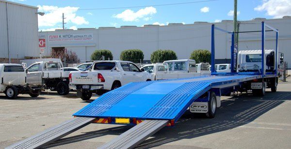 A Blue Flatbed Trailer Is Parked in A Parking Lot Next to A Building — Welshpool, WA — PTE Group Pty Ltd