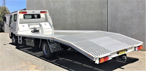 A White Tow Truck with A Flat Bed Is Parked on The Side of The Road — Welshpool, WA — PTE Group Pty Ltd
