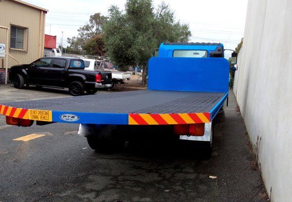 A Blue Flatbed Truck Is Parked in A Parking Lot Next to A Building — Welshpool, WA — PTE Group Pty Ltd