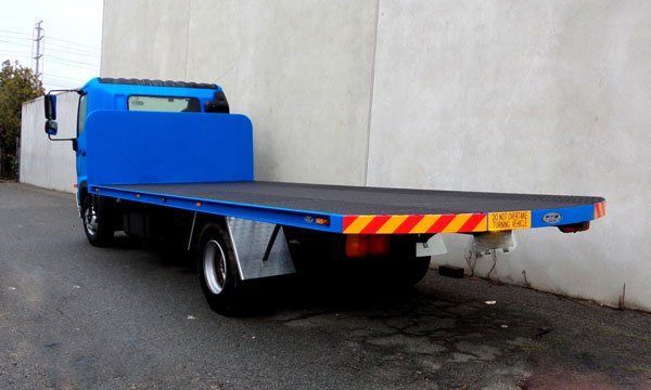 A Blue Flatbed Tow Truck Is Parked in Front of A Building — Welshpool, WA — PTE Group Pty Ltd
