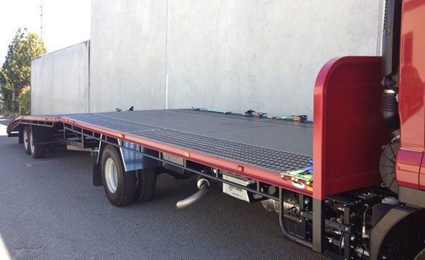 A Red Truck with A Flatbed Trailer Attached to It Is Parked on The Side of The Road — Welshpool, WA — PTE Group Pty Ltd