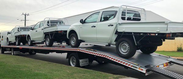 A Row of White Trucks Are Sitting on Top of A Flatbed Tow Truck — Welshpool, WA — PTE Group Pty Ltd