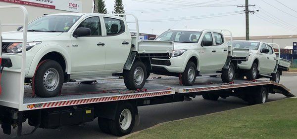 A Row of White Trucks Are Sitting on Top of A Tow Truck — Welshpool, WA — PTE Group Pty Ltd