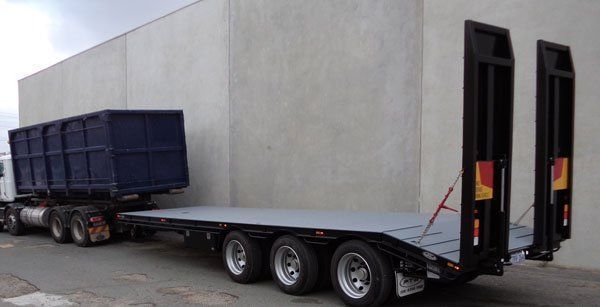 A Semi Truck with A Flatbed Trailer Attached to It Is Parked in Front of A Building — Welshpool, WA — PTE Group Pty Ltd