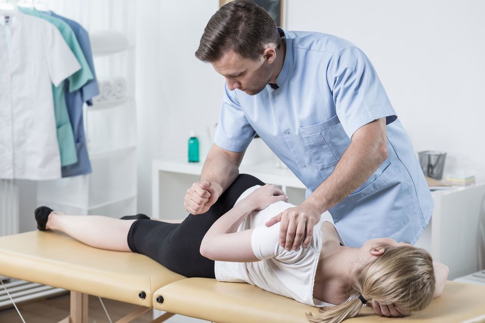 A Man Is Giving A Woman A Massage On A Table — Caves Coastal Physiotherapy in Caves Beach, NSW
