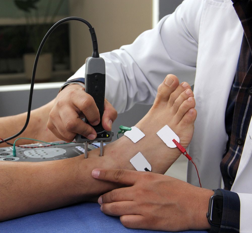 A Doctor Is Using A Device On A Patient's Foot — Caves Coastal Physiotherapy in Caves Beach, NSW