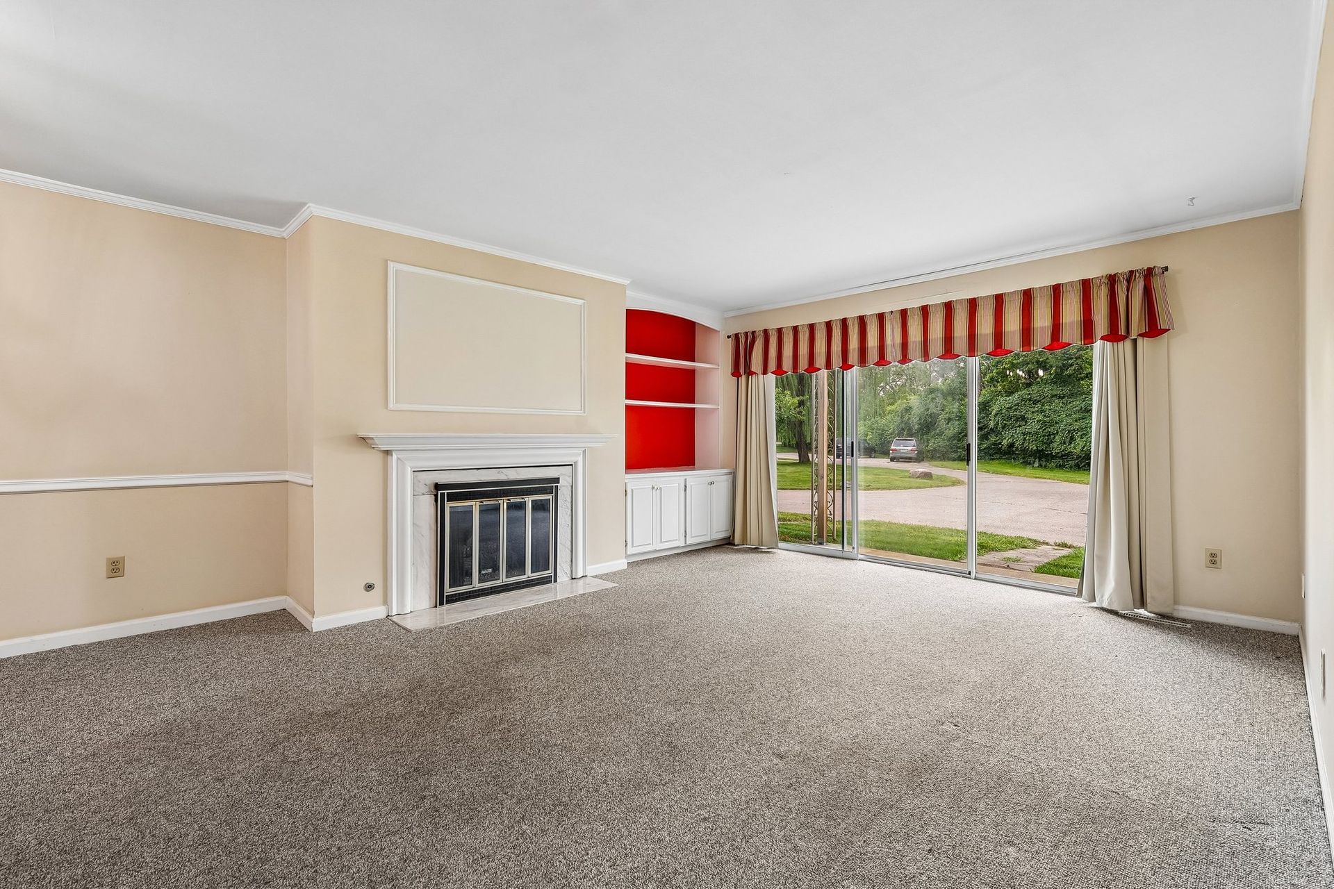 Photo of a living room with a fire place and wide sliding glass door area allowing for plenty of natural lighting